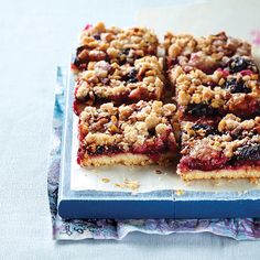 berry crumbled bars cut into squares on top of a white paper towel and blue napkin