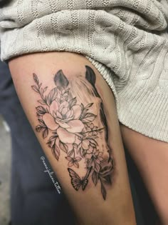 a woman's thigh with flowers and a horse head tattoo on her left leg