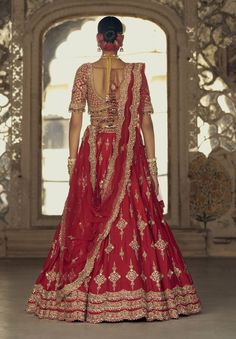 Make a striking impression in this red raw silk lehenga choli, complemented by a net dupatta embroidered in gold dori and highlighted with dabka, beads, sequins, and crystals. It comes with a second beige dupatta and belt. Embroidered Bridal Lehenga, Raw Silk Lehenga, Red Lehenga, Embroidered Lehenga, Indian Wedding Wear, Embellished Blouse, Silk Lehenga, Net Dupatta, Perfect Wedding Dress