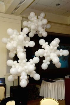 a bunch of white balloons are floating in the air over chairs and table cloths