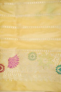 an old yellow cloth with colorful designs on it's edges and some white dots