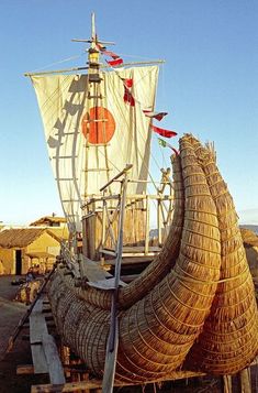 an old boat is sitting in the sand with some straw on it's side