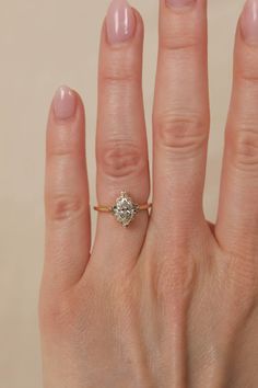 a woman's hand with a diamond ring on top of her finger and the other hand holding an engagement ring