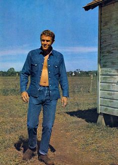 a man standing in the middle of a field wearing a blue shirt and orange tie