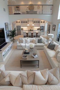 a living room filled with white furniture and lots of pillows on top of the couches