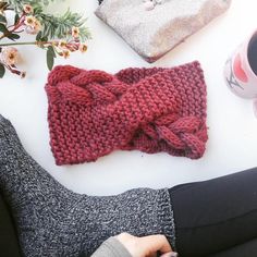 a knitted red bow tie laying on top of a white table next to coffee cups