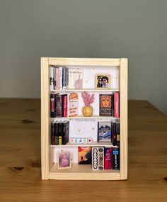 a wooden book shelf with books and magazines in it on top of a wood table