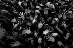 black and white photograph of many hands reaching for each other