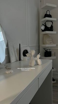 a white desk topped with a mirror next to a shelf