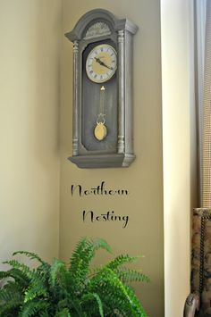 a clock mounted to the side of a wall next to a potted green plant