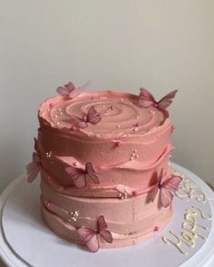 a three layer cake with pink frosting and butterflies