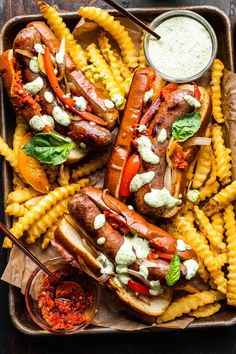 grilled hot dogs and french fries on a platter with dipping sauce in a bowl