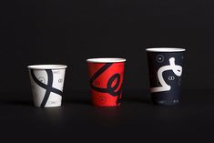 three different types of paper cups on a black surface, one is red and the other is white