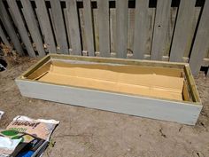 an empty wooden box sitting on the ground next to some construction materials and a fence