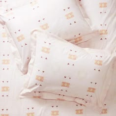 a bed with white sheets and pink pillow cases on top of it, next to an alarm clock