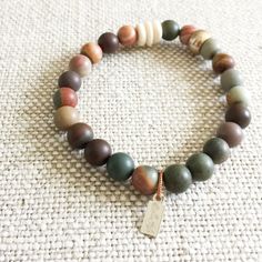 Picasso jasper raw semi-precious round stone bracelet. Colors range from neutrals to olives and grays. Features brass and bone details. Sterling silver BelleStyle logo tag. Comes in linen travel pouch. Made in USA. Earthy Jasper Beaded Bracelets With Natural Stones, Earthy Jasper Beaded Bracelet With Natural Stones, Earthy Beaded Bracelets With Natural Jasper Stones, Earthy Natural Stones Beaded Bracelets, Earthy Hand-strung Beaded Bracelets For Everyday, Earthy Hand-strung Bracelets For Everyday, Earthy Everyday Hand-strung Bracelets, Bracelet Colors, Picasso Jasper