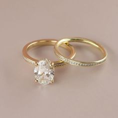 two gold wedding rings with an oval diamond