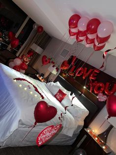 red and white balloons floating from the ceiling above a bed