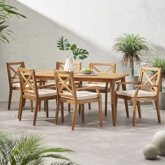 a wooden table and chairs sitting on top of a cement floor next to potted plants