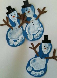 three snowmen made out of paper on a white wall