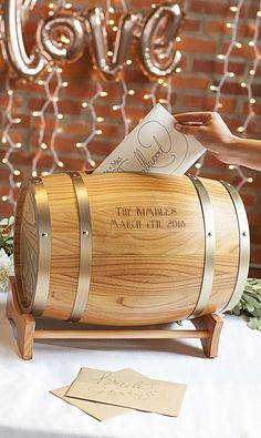 a wooden barrel that is on top of a white table cloth and some lights are in the background