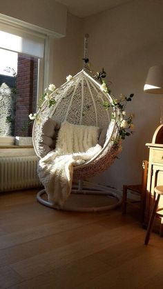 a hammock hanging from the ceiling in a room with wood floors and windows