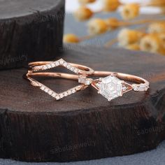 two rose gold wedding rings with diamond accents on top of a wooden table next to other jewelry items