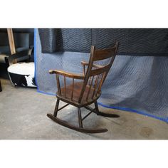 a wooden rocking chair sitting in front of a blue tarp