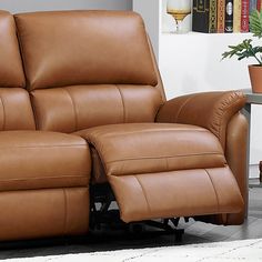 a brown leather reclining sofa sitting on top of a white rug next to a table