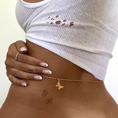 a woman with tattoos on her stomach wearing a white t - shirt and gold bracelet