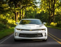 a white chevrolet camaro driving down the road