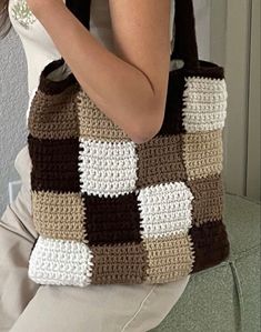 a woman holding a brown and white crocheted bag