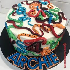 a birthday cake with the number four on it, decorated with colorful snakes and serpents