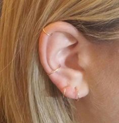 a close up of a woman's ear with a gold ring on the end