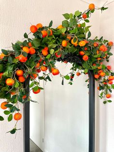 oranges are growing on the top of an arch in front of a white wall