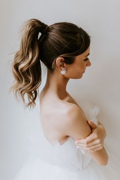 a woman wearing a white dress with her hair in a ponytail