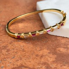 Estate/ Vintage 18KT Yellow Gold Designer Bangle Bracelet with Channel Set Pink/ Red Ruby + Diamonds. Excellent estate condition Hinged Push In, with safety latch, very secure Weight: 19 Grams Diamonds: .90 carat total weight Baguette-Cut Ruby + Diamonds VS clarity; G H Color Measures: 60mm in diameter 4.7-3mm wide front Designer Marked 18KT MW Luxury Red Baguette Diamond Jewelry, Panther Jewelry, White Gold Bracelet, Rose Gold Pendant, White Gold Necklaces, White Gold Earrings, Rose Gold Bracelet, Yellow Gold Bracelet, Diamond Bangle