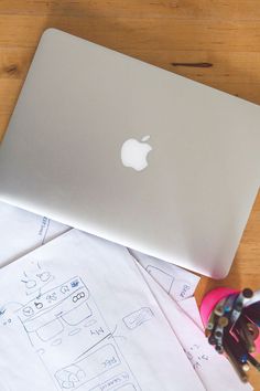 an apple laptop sitting on top of some papers and scissors next to it's case