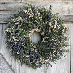 a wreath is hanging on the side of a wooden door with lavenders and rosemary