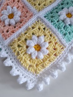 a crocheted granny granny blanket with flowers on it's sides and four squares around the edges