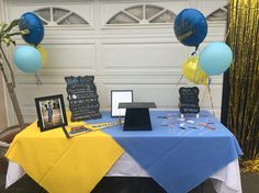 a blue and yellow table topped with balloons next to a white garage door in front of a house