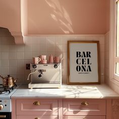 a kitchen with pink cabinets and an art print on the wall next to the stove