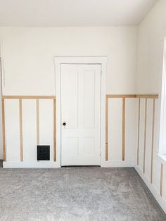 an empty room with white walls and wood trim around the door, carpeted floor