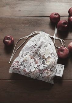 a white lace bag sitting on top of a wooden floor next to red apple's