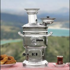 a silver coffee pot sitting on top of a table next to a plate of food