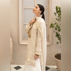 Fabric: Shirt - Chickankari, Dupatta - Chiffon Sharara- Organza Style: Sharara Color: Off-White Work Technique: Embroidery Description: A Chikankari Straight Shirt With Heavy Embroidery. The Dress Also Contains A Flowy White Sharara With Gold Pani On It's Bottom And A Chiffon Dupatta With Gold Work On All Four Sides And Delicate Booti All Over It. Elegant Unstitched Suit With Long Sleeve Lace Work, Elegant Chikankari Embroidered Fabric For Eid, Elegant Embroidered Fabric For Straight Kurta, Elegant Lawn Suit With Lace Work, Elegant Off White Embroidered Dupatta Fabric, Eid Beige Dress With Lace Work, Elegant White Embroidered Fabric With Dupatta, Elegant Lace Work Straight Kurta Lawn Suit, Elegant Georgette Lawn Suit With Lace Work