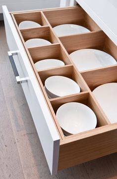 an open drawer with white plates in it