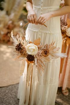 a woman in a white dress holding a basket with flowers and feathers on the side