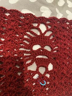 a red crocheted scarf laying on top of a white and gray table cloth