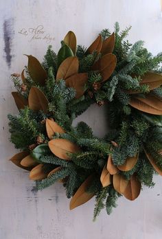 a wreath is hanging on the wall with leaves and pineconi around it,